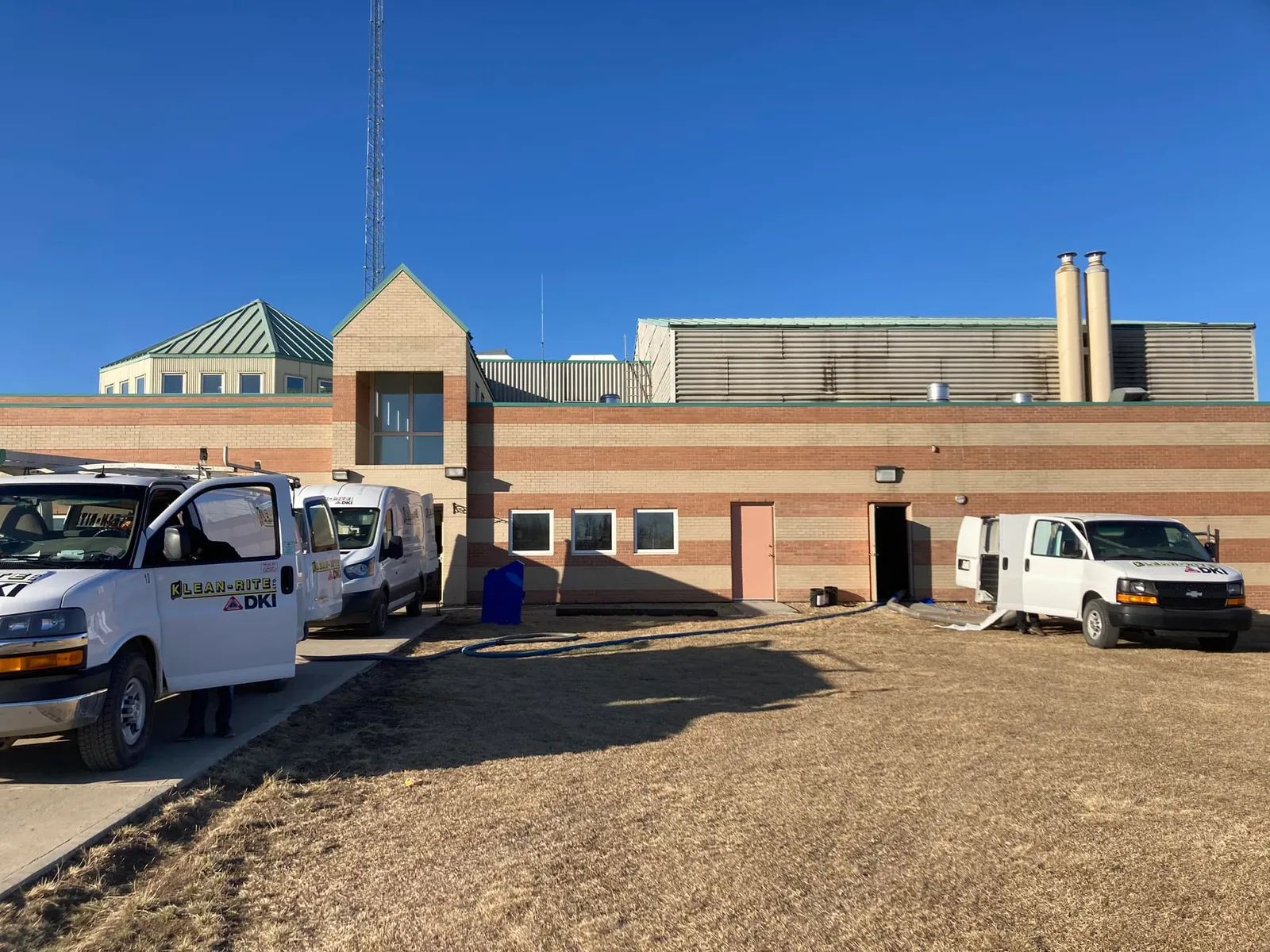 Klean-Rite DKI service vans parked outside a commercial building with equipment hoses run inside